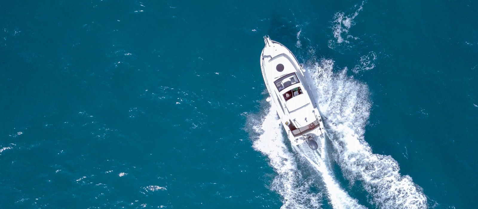 A boat leaving a white wake across the blue Andaman Sea